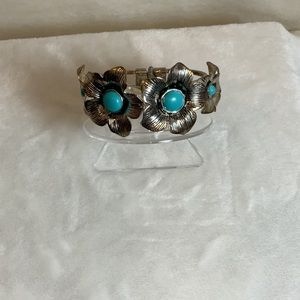 Silver tone, hinged cuff bracelet with flowers and turquoise colored stone.